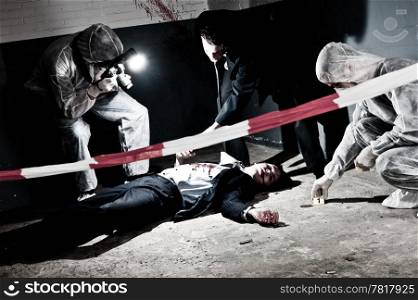 A cross processed murder scene with two forensic analysts and a police lieutenant investigating a crime on a businessman in a basementMurder scene with two forensic analysts and a police lieutenant investigating a crime on a businessman in a basement