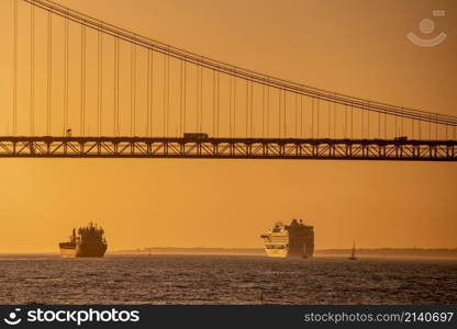 a Cruise Ship in front of the Ponte 25 de Abril or 25the April Bridge on the Rio Tejo near the City of Lisbon in Portugal. Portugal, Lisbon, October, 2021