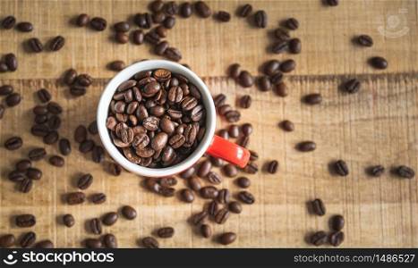 A cup full of coffee beans on a wooden mangocoffee table. Coffee concept, table top. A cup full of coffee beans on a wooden mangocoffee table