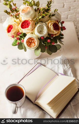 A cup of black tea, notebook and beautiful flowers on the table. Morning inspiration for the day planning. Inspiration for solving difficult problems