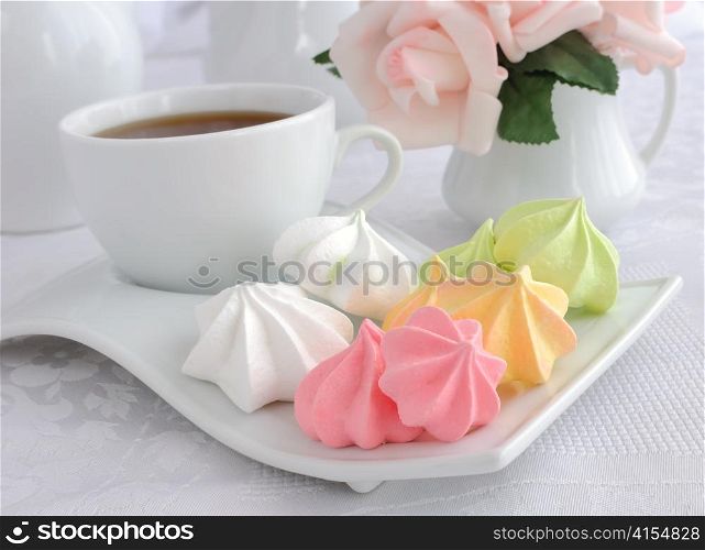 A cup of coffee and biscuits meringue on a plate closeup