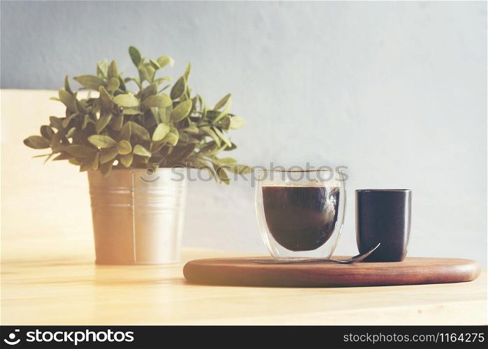 a cup of coffee and little tree on wooden table in Coffee shop