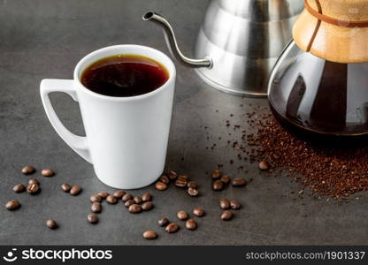 A cup of coffee and third generation pour over coffee brewing equipment on stone floor