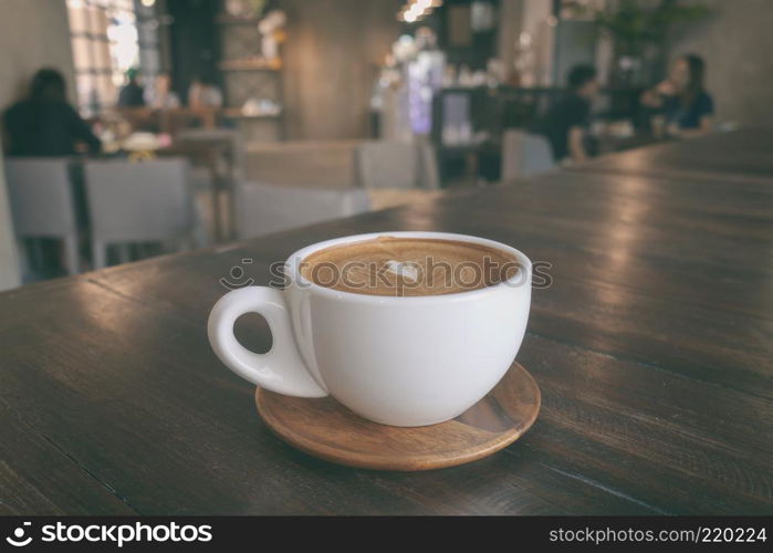 A cup of coffee latte on wooden table in warm cafeteria