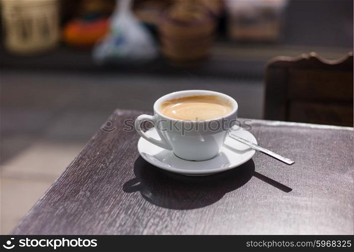 A cup of coffee on a table outside in the street
