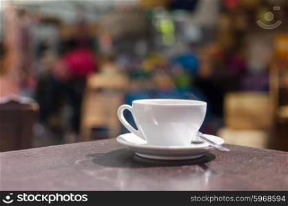 A cup of coffee on a table outside in the street