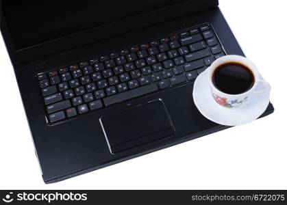 A cup of coffee on laptop keyboard isolated in white background