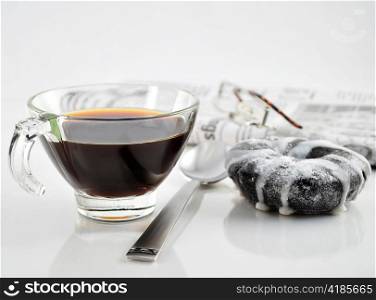 a cup of coffee with donut and newspaper