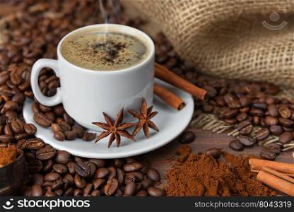 A cup of coffee with spices on the background of coffee beans