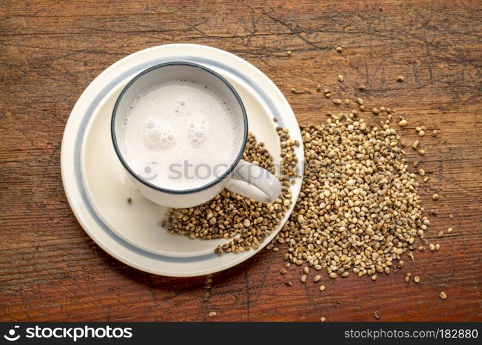 a cup of hemp milk and hemp seeds on a grunge wood