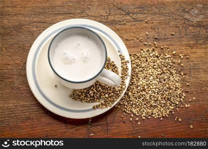 a cup of hemp milk and hemp seeds on a grunge wood