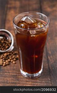 A cup of Iced Americano Coffee with ice cubes placed on a wooden table in a coffee shop. Top view of a glass of coffee.