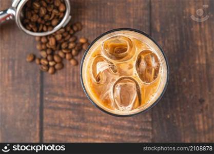 A cup of Iced Latte Coffee with ice cubes placed on a wooden table in a coffee shop
