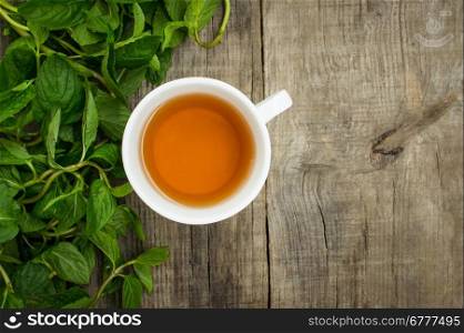 A cup of mint tea on wood textured background
