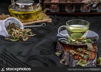 A Cup of pandan leaf tea, indian marsh fleabane plant leaves with Safflower dried (Saffron substitute) at dark background. Thai herbal plant and healthy drinks concept. Selective focus.
