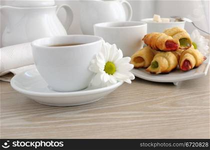 A cup of tea with homemade croissants filled with colorful jelly
