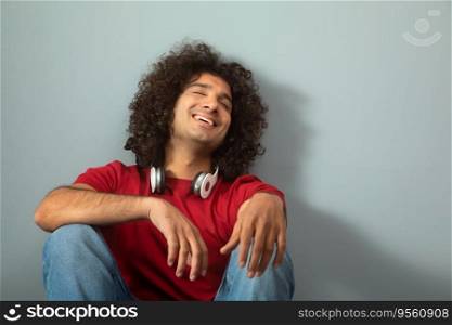 A CURLY HAIRED YOUNG MAN HAPPILY SITTING ALONE