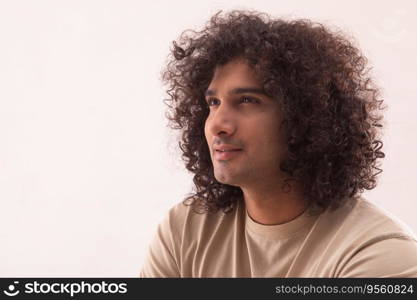 A CURLY HAIRED YOUNG MAN LOOKING AWAY AND THINKING