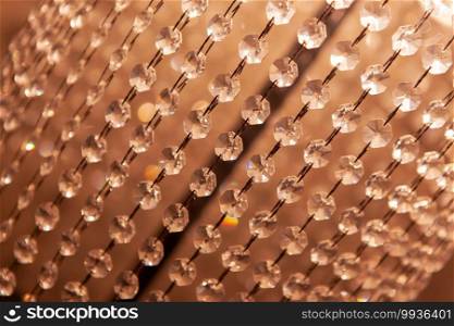 A curtain of transparent glass crystals, decoration on a l&, close-up, a background of hanging beads. Concept abstract texture, interior details, room lighting. Side view. Diagonal composition.