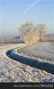 A curving ditch, surrounding a frosted field on a clear winter day