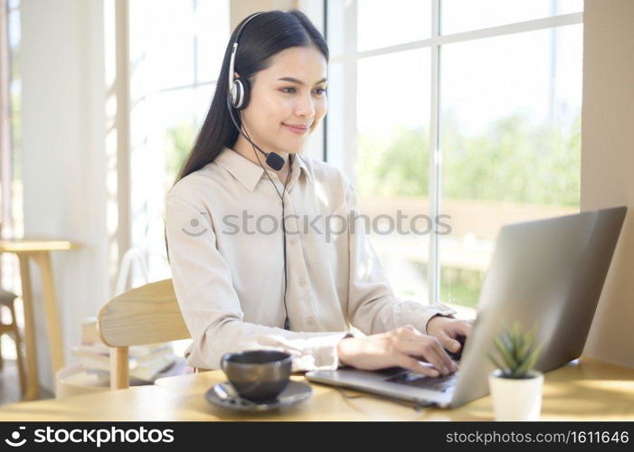 A customer service operator woman in headset using computer answering customer call in office. Customer service operator woman in headset using computer answering customer call in office