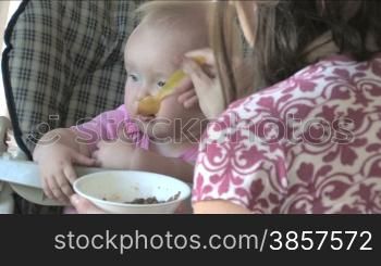 A cute 10-month-old baby eats a spoonful of food then bounces up and down in excitement