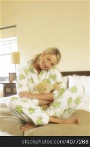 A cute 30&acute;s woman in bed sleeping and cuddling a teddy bear. She is wearing her pajamas
