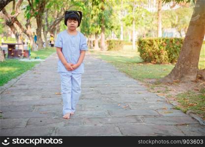 A cute Asian boy or girl walks in peace and relaxes in the garden pavilion at the temple or church and wears a white dress with sunlight on a white background