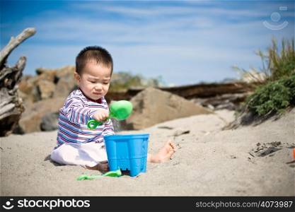 A cute asian boy playing with sand on the beach
