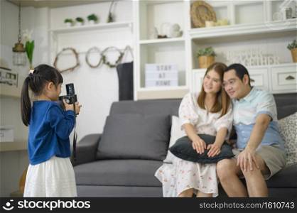 a cute Asian daughter holding camera is taking photos of her parents at home on weekends.