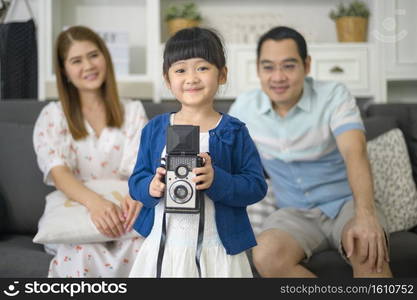 a cute Asian daughter holding camera is taking photos of her parents at home on weekends.