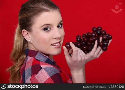 A cute blond eating grapes.