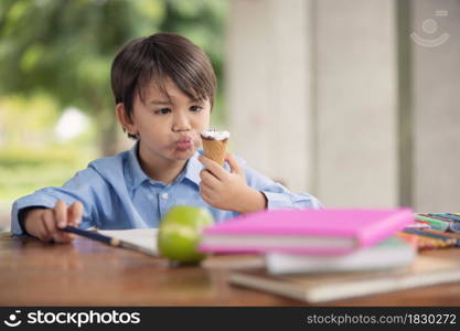 A cute boy eating with ice cream cone during homework breaks at home during covid 19 lock down,Home schooling,Social Distance.