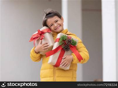 A cute boy in winter coat holding gift box and smiling. preparing for Christmas holiday