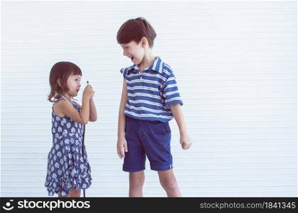 A cute caucasian little sister pretends to be doctor and giving injection to his brother