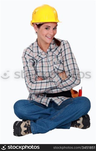 A cute female construction worker sitting on the floor.