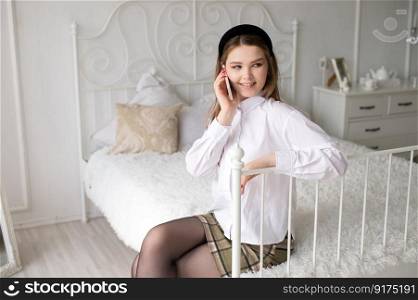 A cute girl in a white shirt and a red manicure is sitting in the room and answering the phone. A cute girl in a white shirt and a red manicure is sitting in a room and talking on the phone