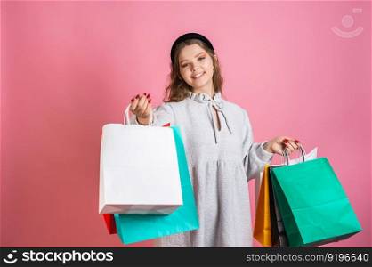 A cute girl is standing with paper bags of different colors. Cute girl holding bright paper bags and smiling