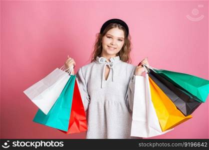 A cute girl is standing with paper bags of different colors. Cute girl holding bright paper bags