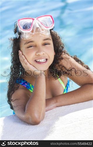 A cute happy young interracial African American girl child relaxing on the side of a swimming pool smiling &amp; wearing pink goggles