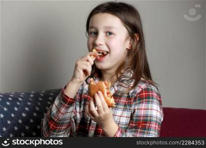 a cute little girl emotionally eating a hamburger, sandwich, cheeseburger or burger and smiling at home.. a cute little girl emotionally eating a hamburger, sandwich, cheeseburger or burger and smiling at home
