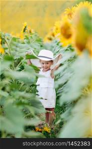 A cute little smiling girl in the field of sunflowers. child in momy hat. childhood concept. Sunny summer day in field of sunflowers. selective focus.. A cute little smiling girl in the field of sunflowers. child in momy hat. childhood concept. Sunny summer day in field of sunflowers. selective focus