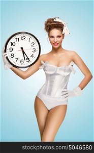 A cute pin-up girl with a vintage hairstyle holding an office wall clock and showing the time.
