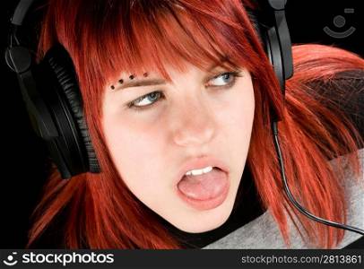 A cute redhead girl expressing boredom while listening to music, disliking it. Studio shot.