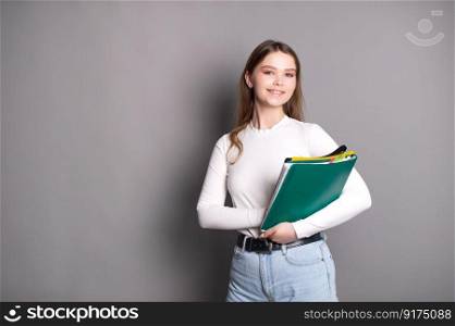 A cute student girl holds notebooks for notes and smiles.. A cute student girl holds notebooks for notes and smiles