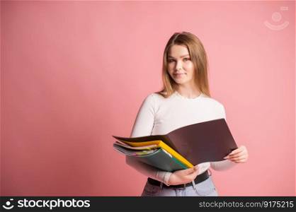 A cute student girl with an open folder for documents stands on a pink background.. A cute student girl with a set of folders for documents stands on a pink background
