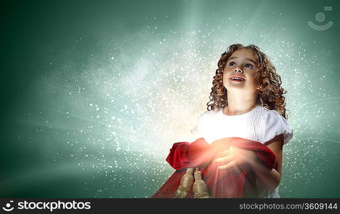 A cute young girl holding a christmas gift, dark background with christmas light bokeh