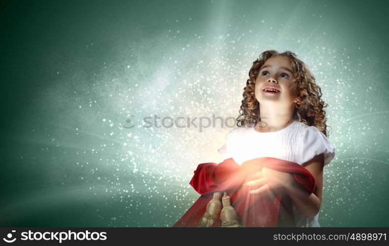 A cute young girl holding a christmas gift, dark background with christmas light bokeh