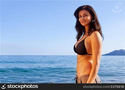 A dark caucasian woman against an ocean landscape
