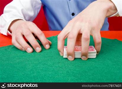 A dealer grabbing a deck of poker cards